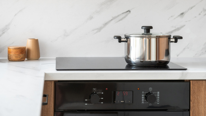 Une cuisine minimaliste impeccable, dotée d'une cuisinière électrique avec une casserole posée dessus