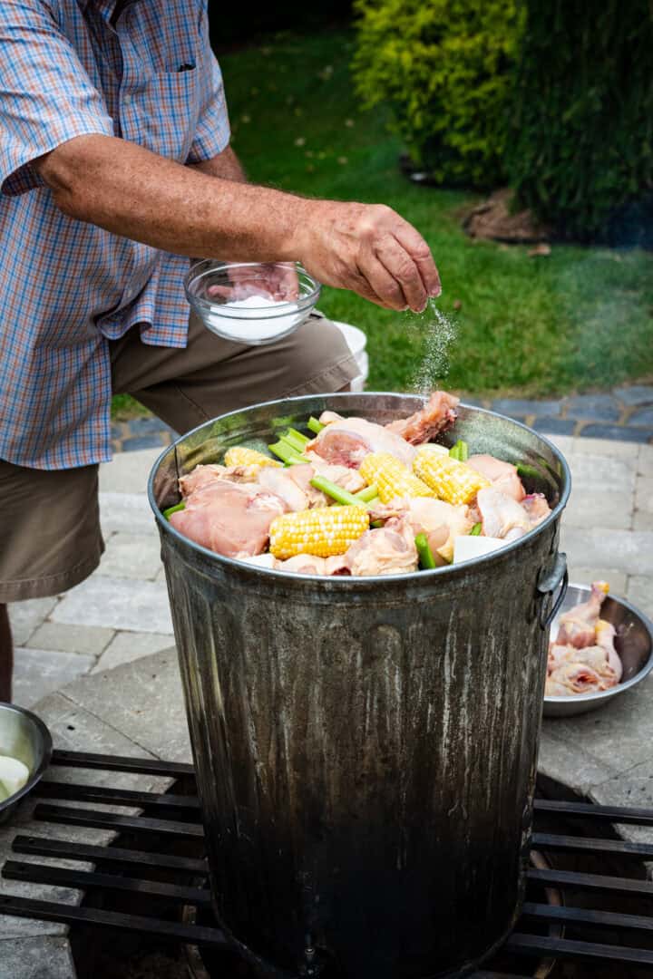 Saupoudrer du sel dans une poubelle remplie de maïs, de poulet et de palourdes.