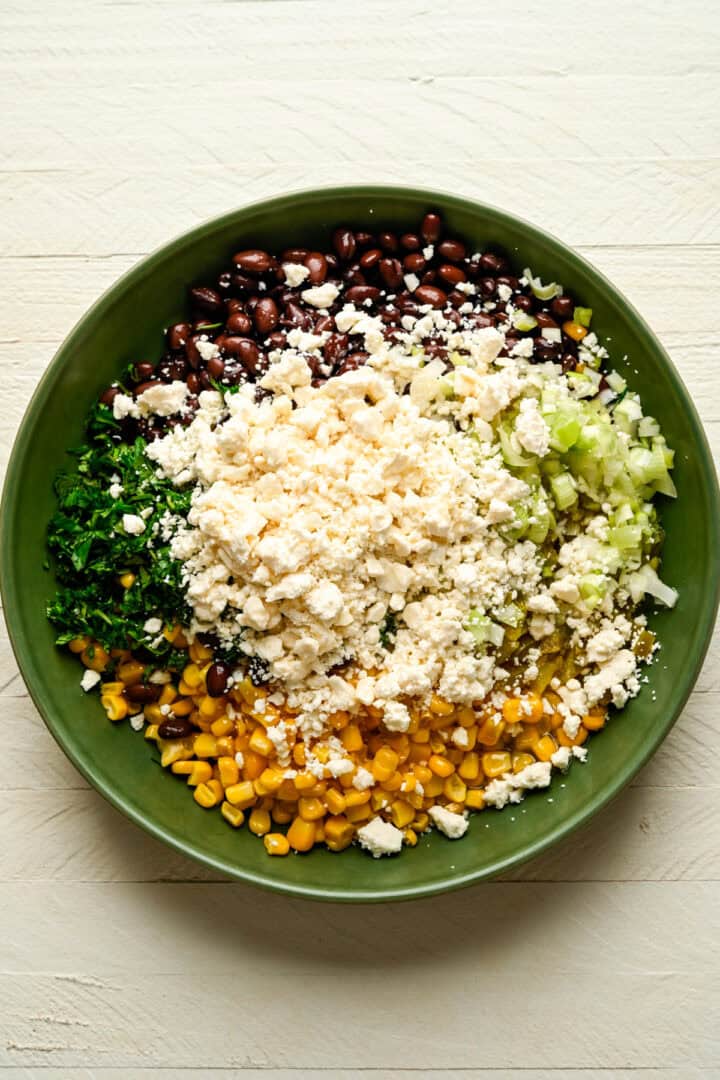 Les haricots noirs, le maïs et la feta trempent les ingrédients dans un bol avant de les mélanger.