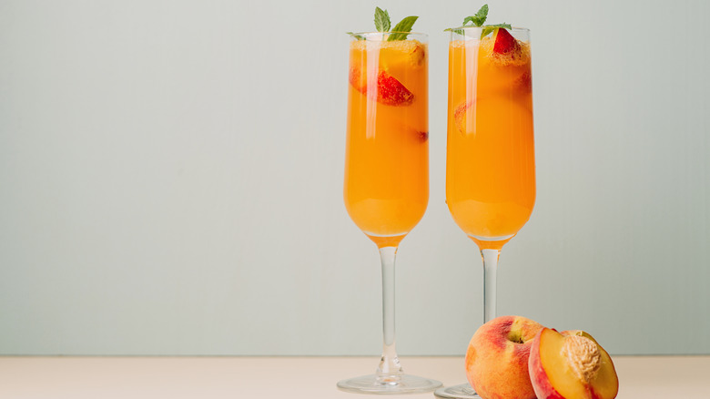 Deux cocktails bellini dans des flûtes à champagne avec garniture de pêche et de menthe
