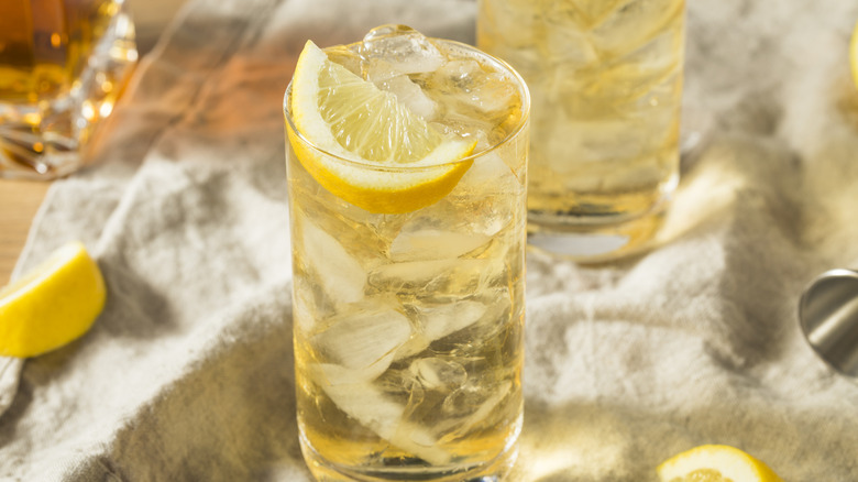 Un cocktail 7 et 7 dans un verre highball garni d'un citron