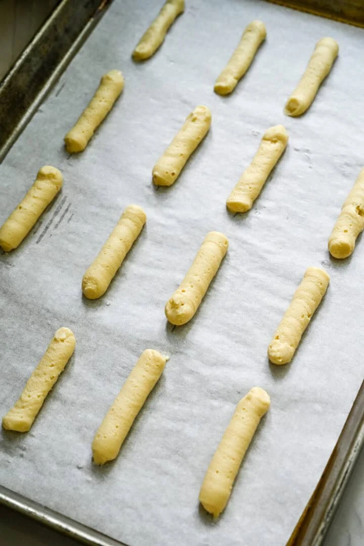 pâte à biscuits milano disposée en lignes droites sur une plaque à pâtisserie.