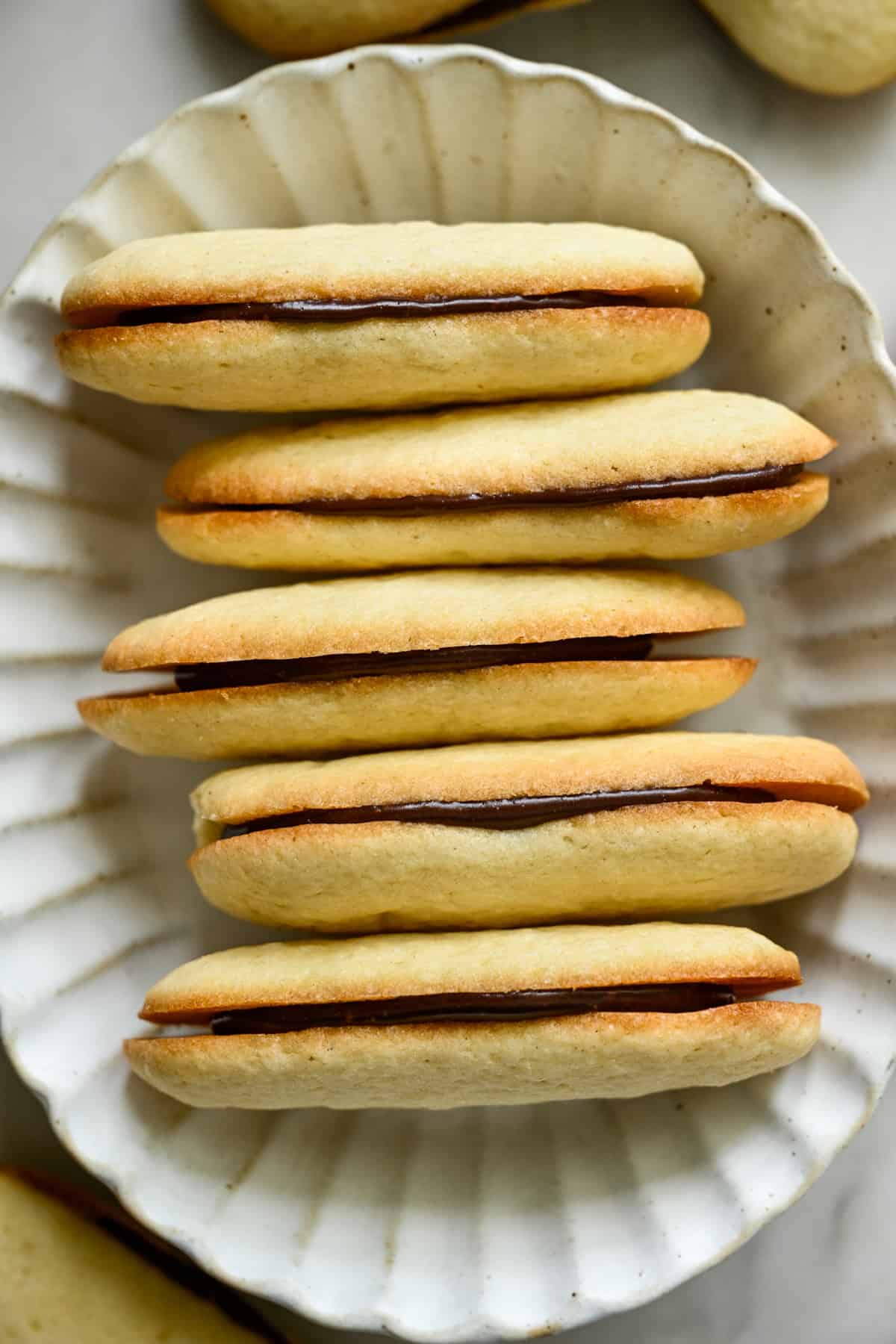 vue aérienne d'une pile de biscuits milanais faits maison dans un bol ovale blanc.