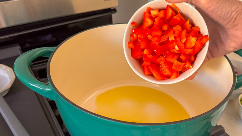 main ajoutant du poivron rouge au pot