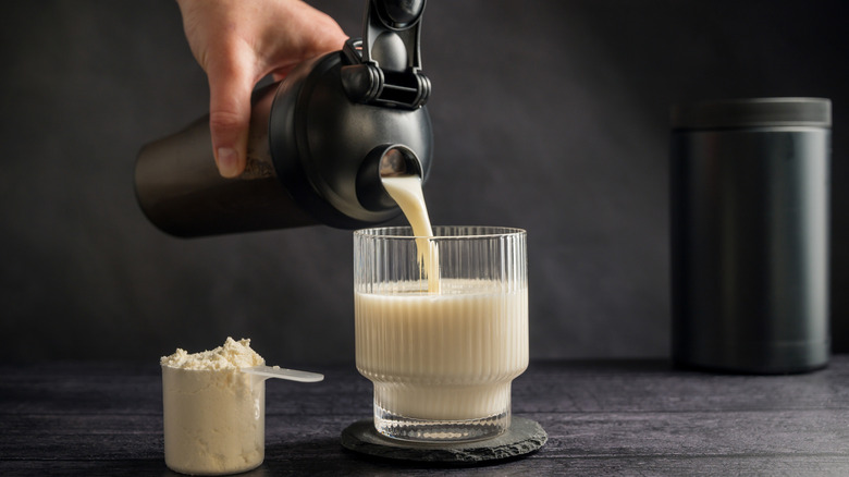 Boisson protéinée. Verser un shake protéiné dans un verre. Fond sombre.