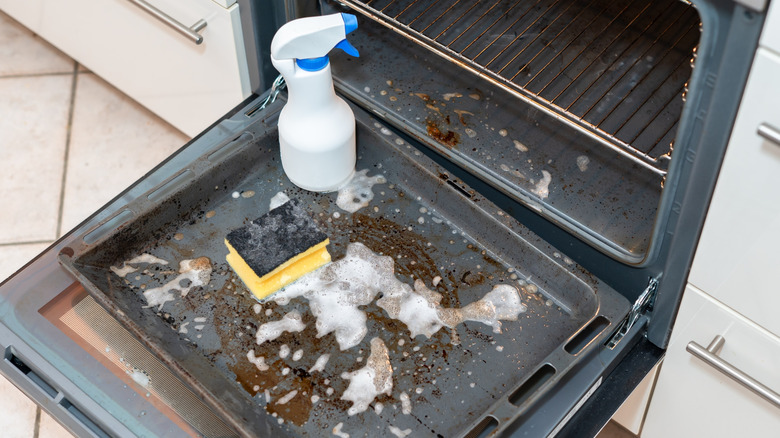 Une plaque de four sale avec un nettoyant mousse.