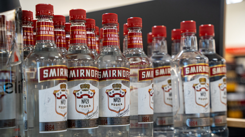 De nombreuses bouteilles de vodka Smirnoff sur une étagère de magasin.