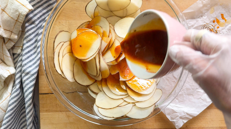 main versant la sauce sur les pommes de terre