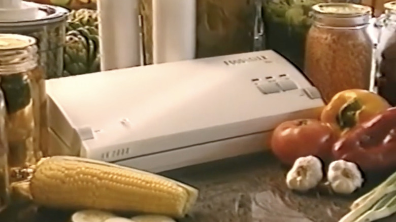 Modèle FoodSaver des années 1990 sur un comptoir de cuisine entouré de légumes dans une publicité informelle