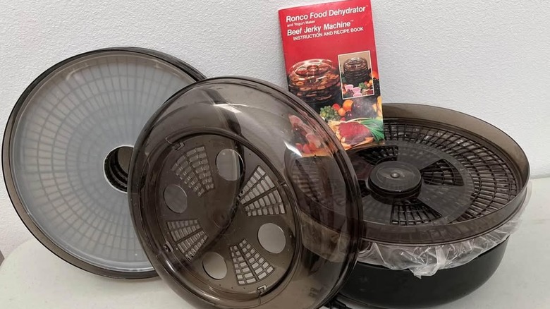Déshydrateur alimentaire Ronco démonté des années 1990 avec manuel d'instructions sur une table
