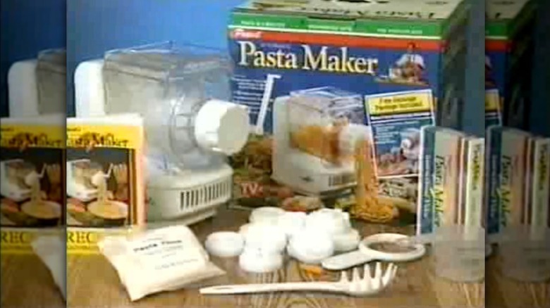 Machine à pâtes Ronco des années 1990 et accessoires assortis disposés sur une table pendant l'infopublicité