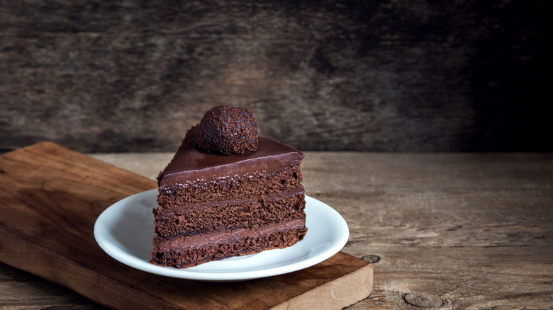 Tranche de gâteau au chocolat sur une assiette blanche sur une planche de service en bois