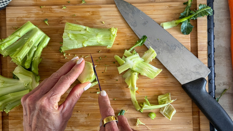 mains coupant les tiges de brocoli avec un couteau