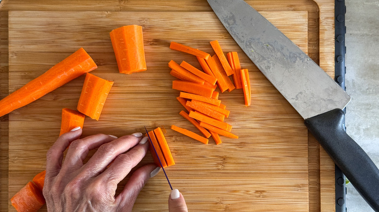 trancher les carottes à la main sur une planche à découper