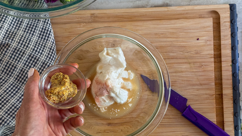 main ajoutant de la moutarde au bol avec de la mayonnaise