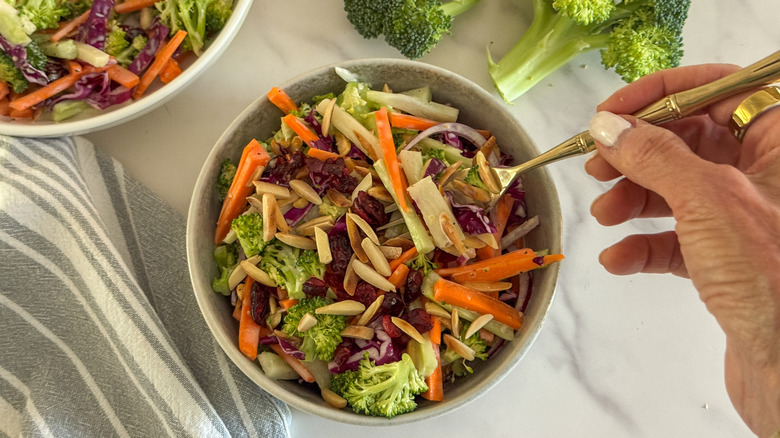 main avec une fourchette dans une salade de brocoli
