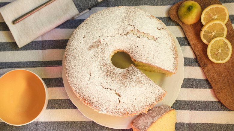 Photo aérienne d'un gâteau en mousseline de citron sur un torchon rayé avec des tranches de citron