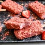 2 strawberry shortcake ice cream pops stacked on top of each other with a bite taken out of the top one.