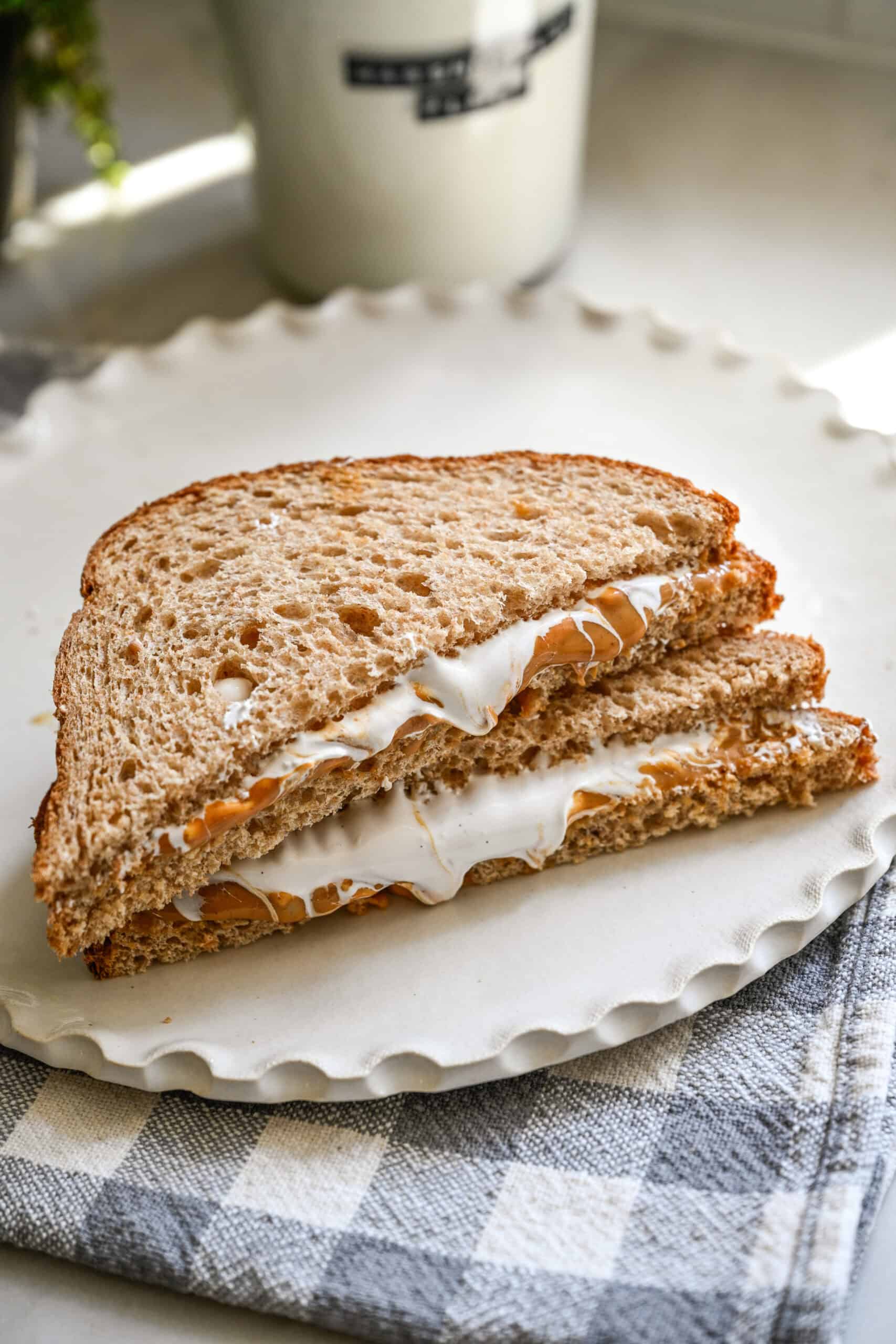 Sandwich Fluffernutter avec beurre de cacahuète et peluches de guimauve coupé en deux sur une assiette.