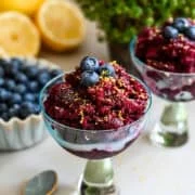Granita aux bleuets dans un verre à cocktail garni de bleuets et de zeste de citron.