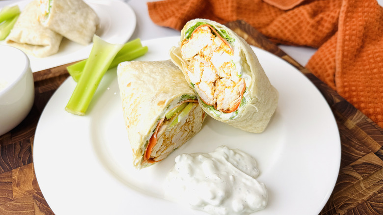 Wrap au poulet Buffalo coupé en deux sur une assiette avec vinaigrette au céleri et au fromage bleu