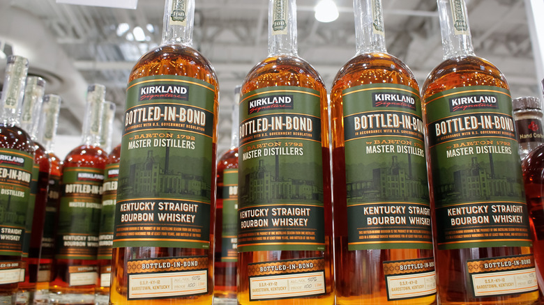 De nombreuses bouteilles de whisky Bourbon droit Kentucky Bottled-in-Bond de Kirkland Signature se trouvent sur les étagères d'un entrepôt Costco.