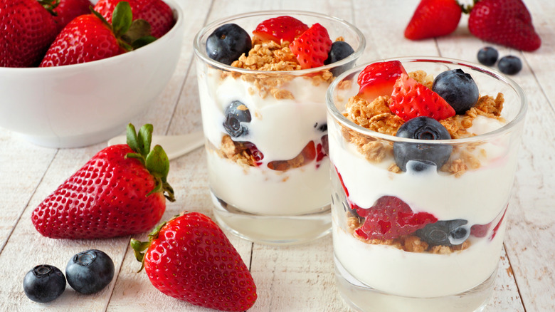 Parfaits au yaourt avec fraises, myrtilles et granola entourés de baies supplémentaires