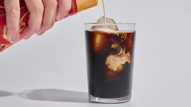 Verser à la main la crème dans le café glacé