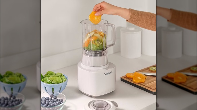 Personne mettant une tranche d'orange dans un mélangeur Cuisinart Soho
