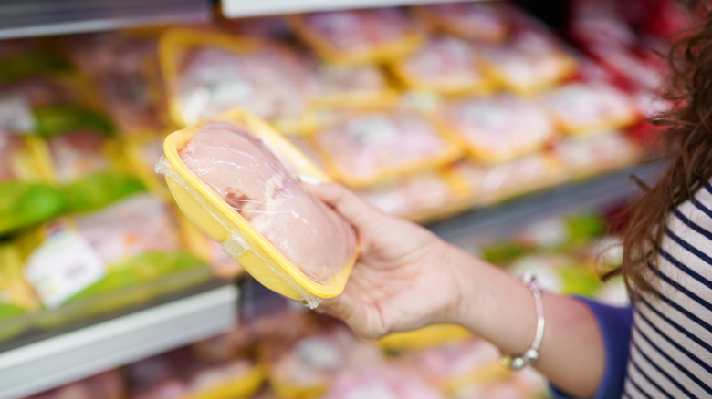 Un client tient du poulet cru emballé à l’épicerie