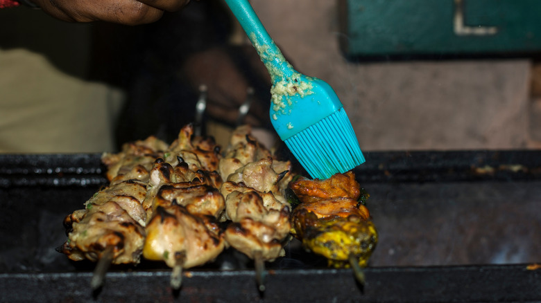 Les brochettes de poulet sont badigeonnées de beurre et d'ail