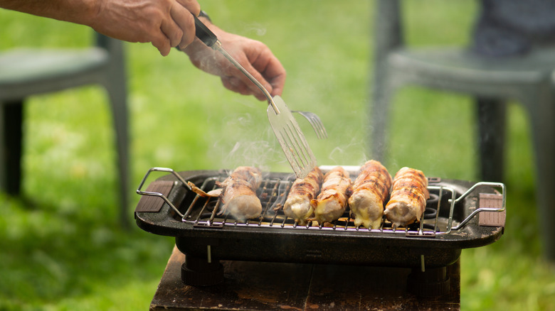 Les brochettes de poulet sont retournées sur un grill