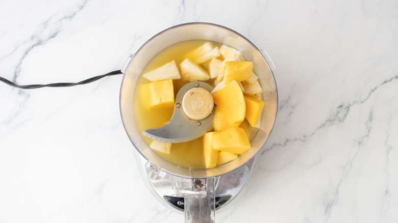 Morceaux de mangue et d'ananas dans un robot culinaire