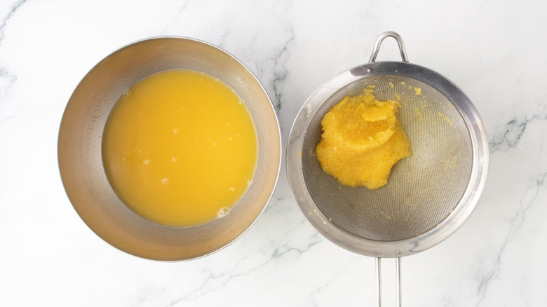 Jus de fruits tropicaux dans un bol à côté de la pulpe dans une passoire
