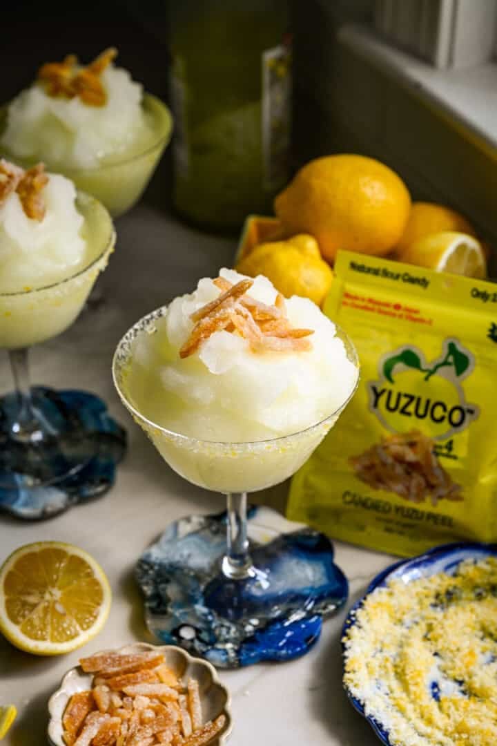 vue rapprochée d'un cocktail de limoncello surgelé dans un verre coupé avec garniture de zeste de yuzu confit.