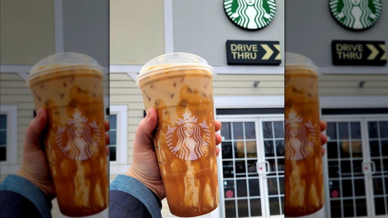Main tenant une infusion froide de crème sucrée avec un filet de caramel