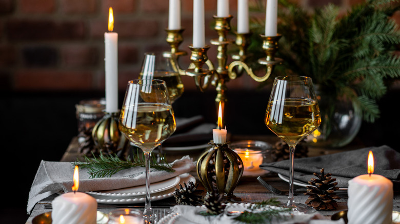 Une table élégante pour un dîner avec des candélabres, des bougies avec des supports décoratifs, des verres à vin et des assiettes