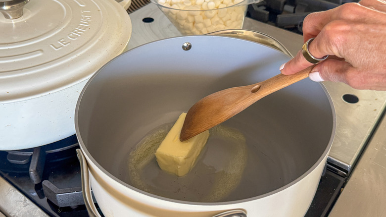 main en remuant le beurre dans une casserole