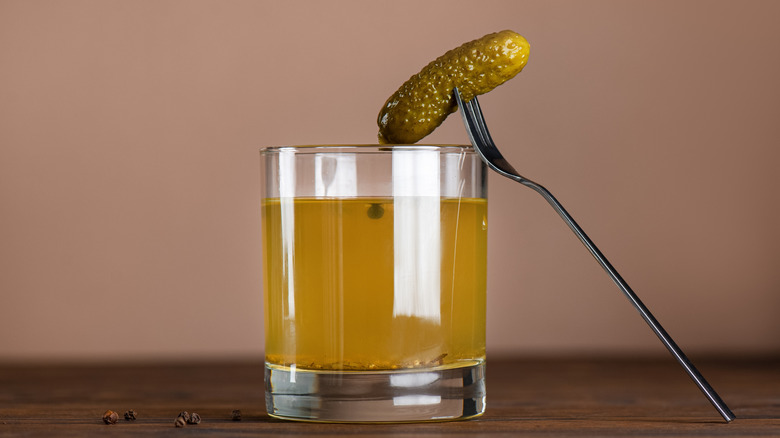 cornichon sur une fourchette sur un verre de jus de cornichon