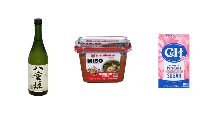 Une bouteille de saké, un contenant de pâte miso et du sucre sur fond blanc isolé