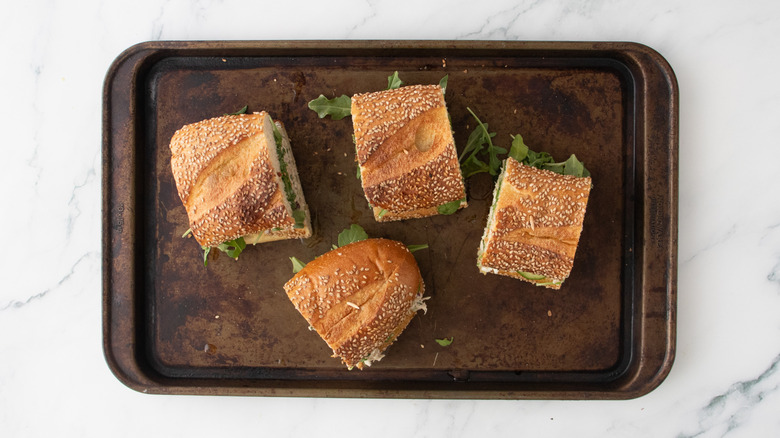 Quatre portions de sandwichs à la salade de thon sur une plaque à pâtisserie.
