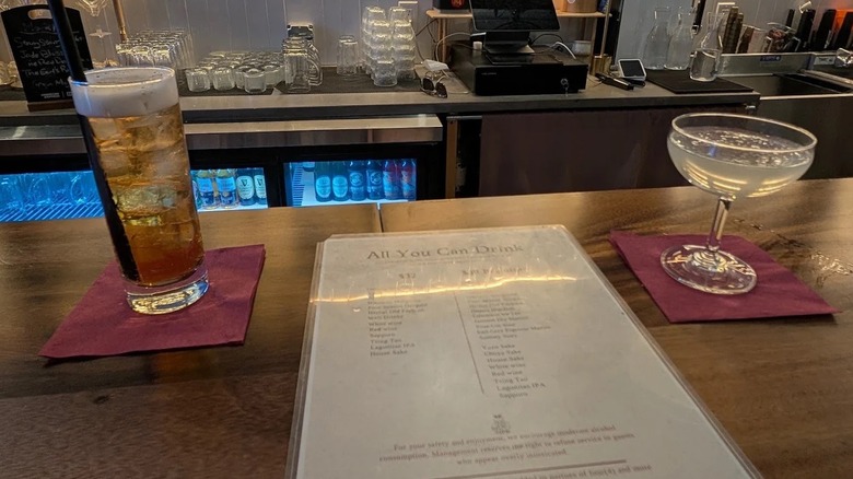 Un menu de bar se trouve au sommet du bar du Huuma à New York, aux côtés de deux cocktails