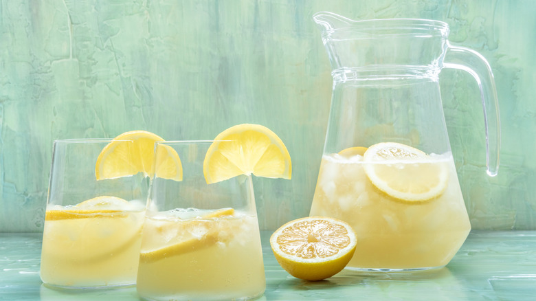 Un pichet d'un cocktail de limonade rafraîchissant avec deux verres déjà servis et garnis de quartiers de citron