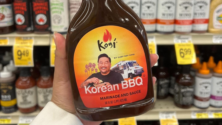 Une main tient la sauce BBQ Kogi.