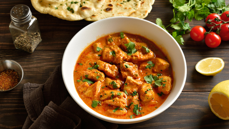 Bol de poulet tikka masala avec naan, épices, tomates, coriandre et citron en accompagnement