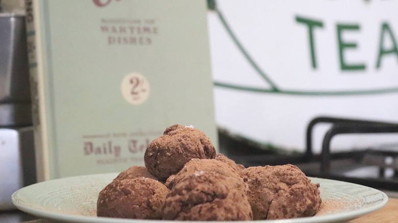 Truffes au chocolat faites avec de la purée de pommes de terre sur une assiette avec le livre de recettes en arrière-plan.