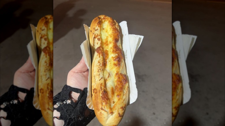 Main de femme tenant un hot-dog dans une baguette garnie de fromage