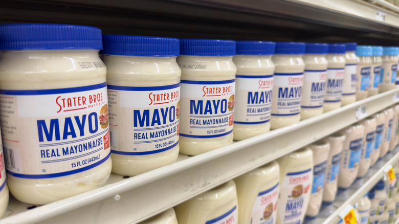 Des pots de mayonnaise alignés sur une étagère de supermarché.