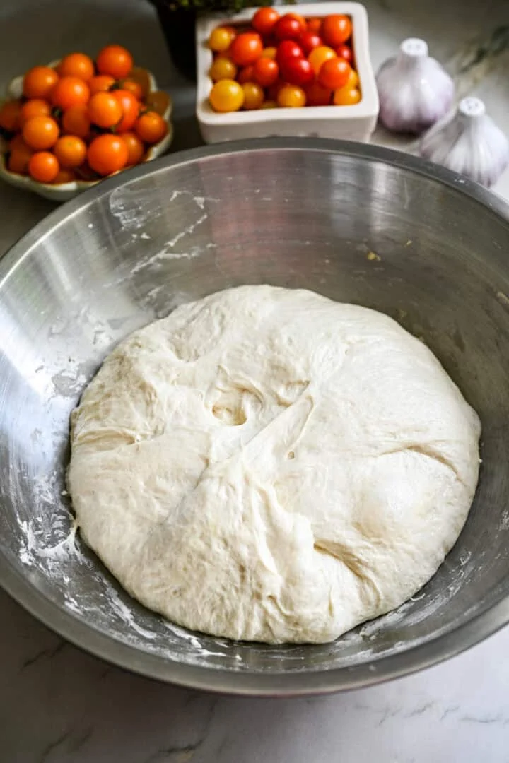 pâte à focaccia levée dans un bol en acier inoxydable.
