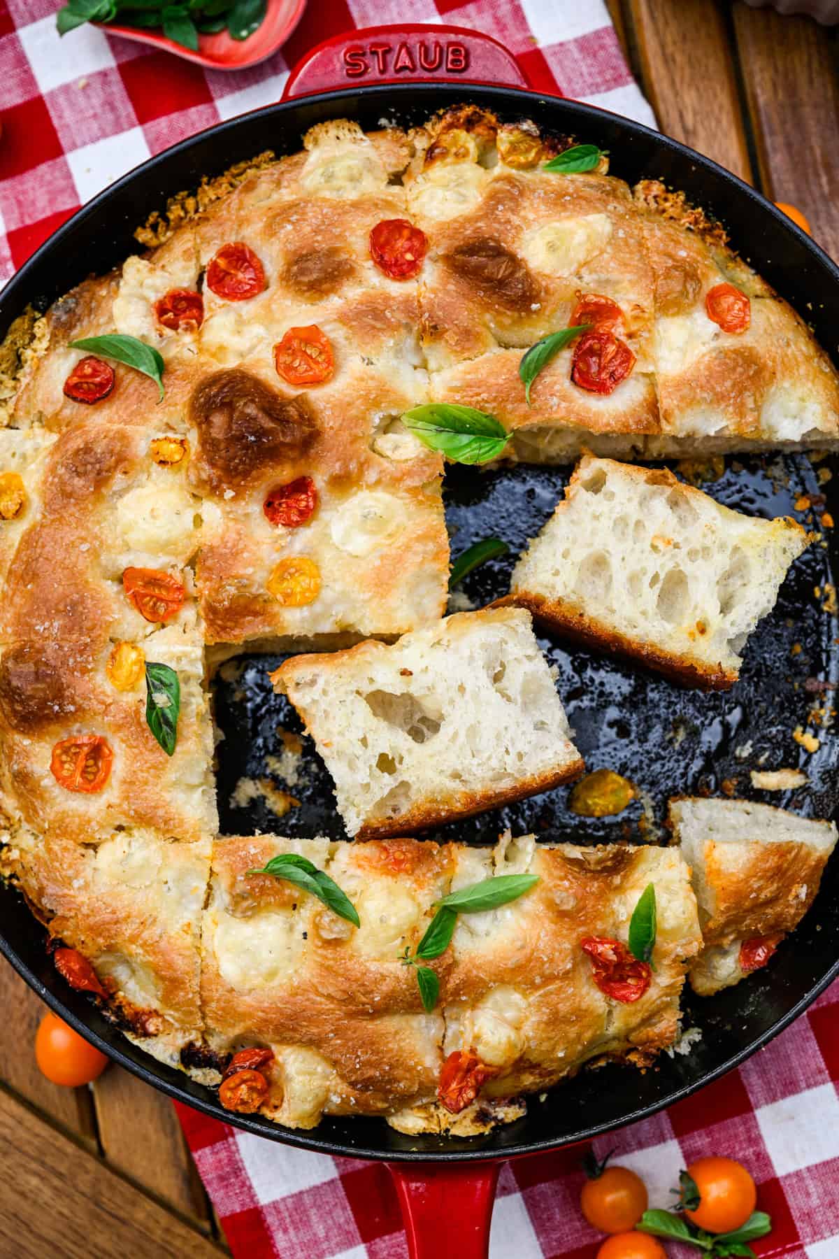Focaccia aux tomates et au basilic dans une poêle avec deux tranches posées sur les côtés.
